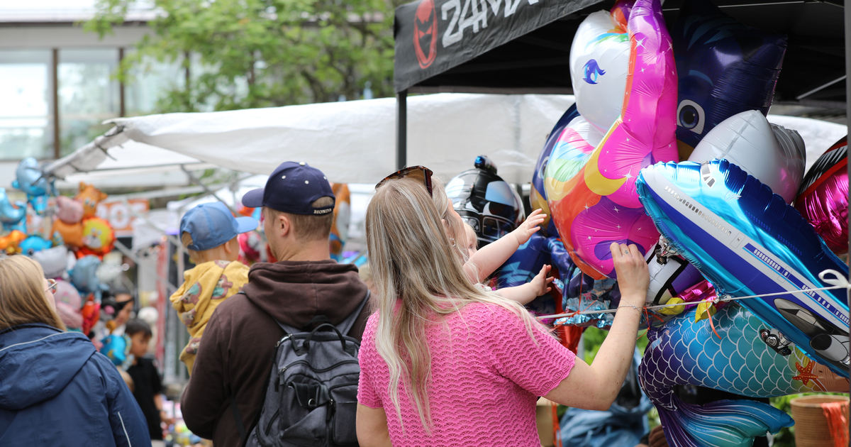 Familj framför marknadsstånd med ballonger