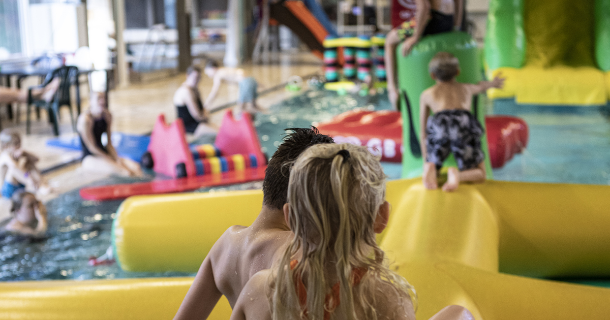 Barn klättrar på en stor, uppblåsbar bana i en simbassäng.