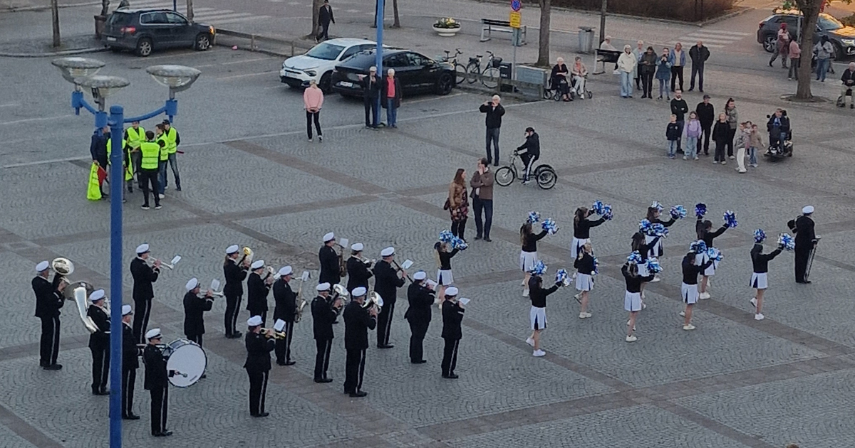 Orkester med drillflickor på ett torg uppställda för marsch.