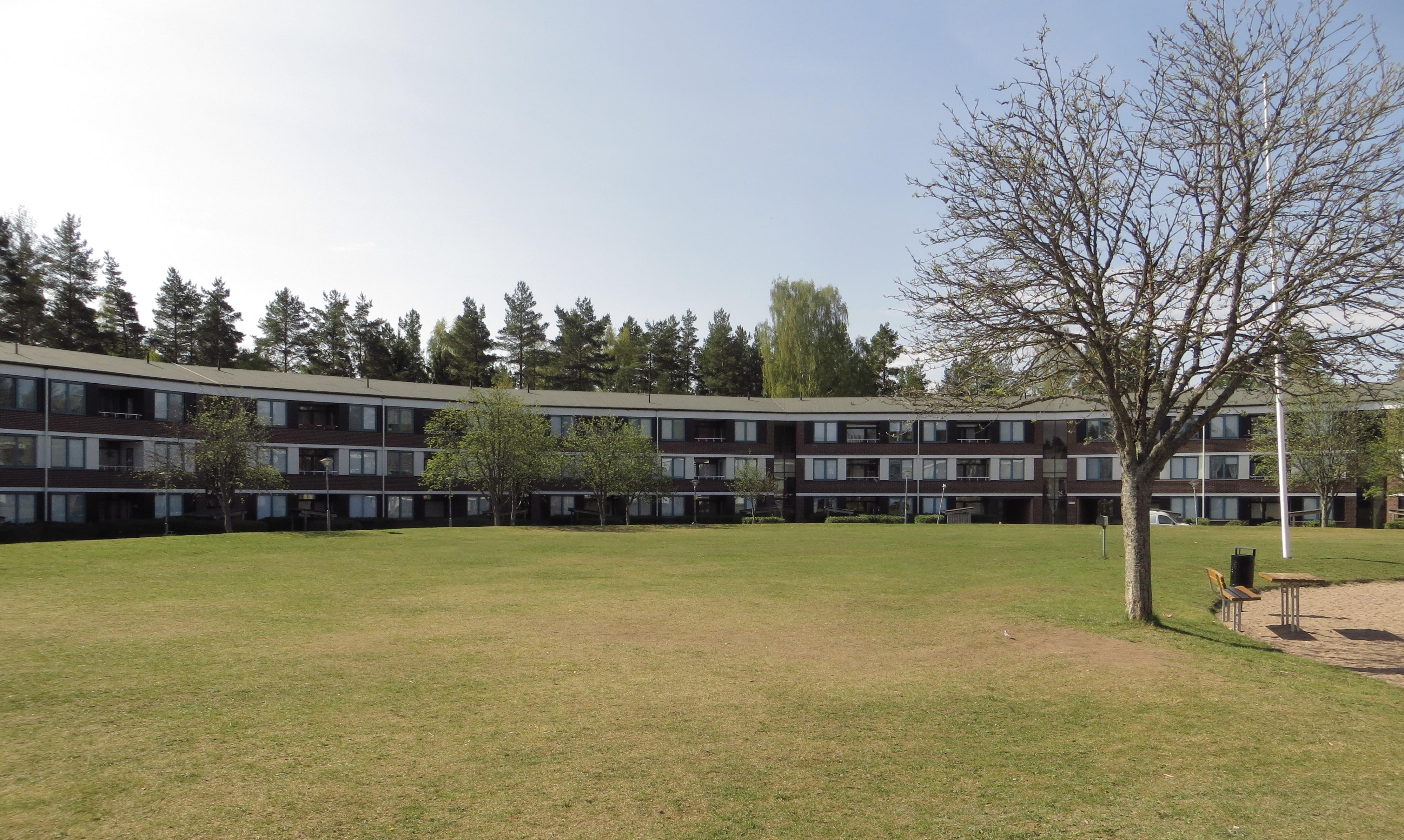 Foto av det cirkelformade flerbostadshuset Kantarellen med en stor gräsmatta i förgrunden