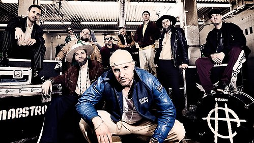 Medlemmarna i Hoffmaestro sitter och står bland förstärkare, trummor och annan utrustning.